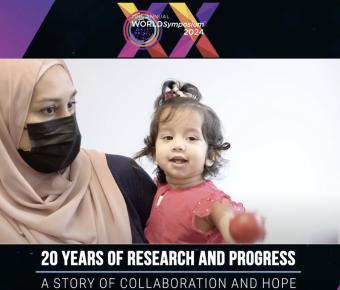 A woman in a hijab and face mask holding a young child at the 17th annual world symposium 2024, celebrating two decades of research and progress.