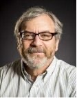 Michael Gelb, PhD, Washington University, smiling in light grey top with light grey hair and beard on grey backdrop