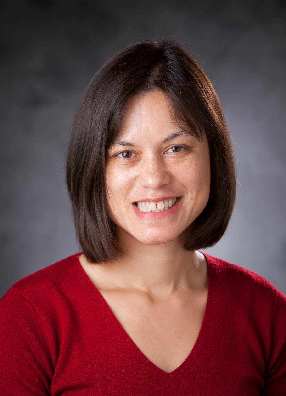 Sarah Young smiles with grey background